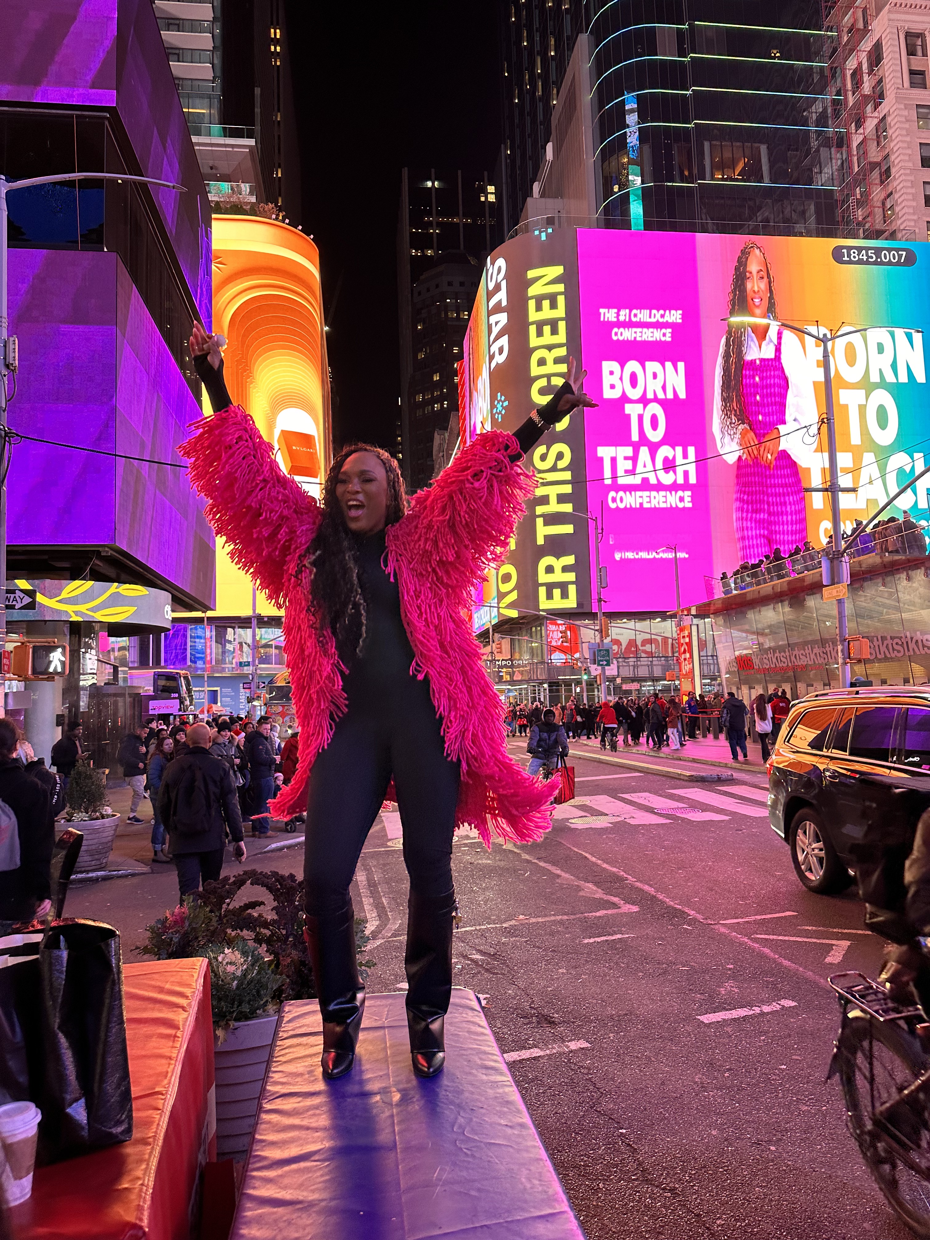 Author celebrating in Times Square beneath a Born to Teach conference billboard