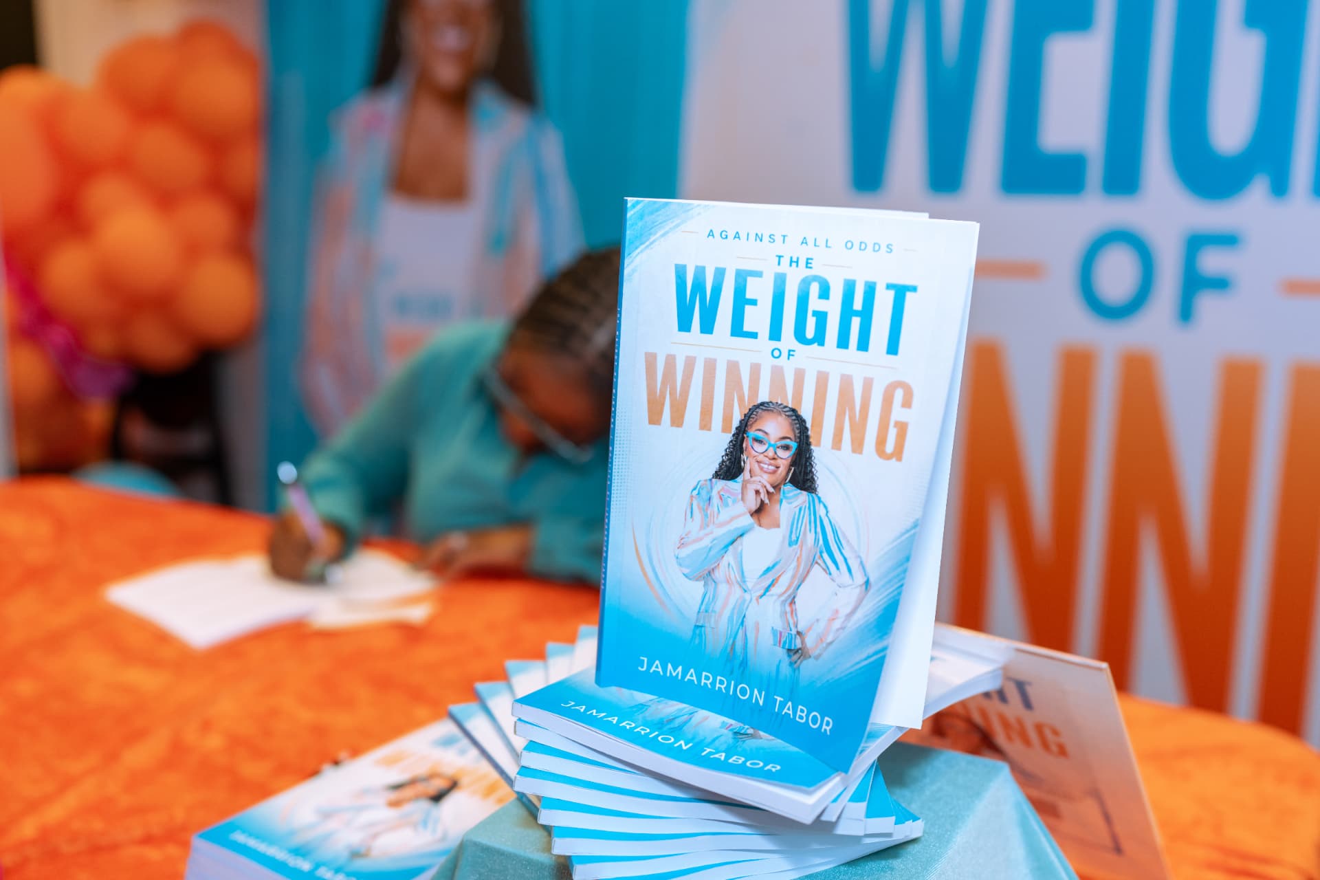 Copies of The Weight of Winning by Jamarrion Tabor stacked on a book signing table
